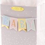 Hallmark medium baby gift bag with a "BABY" banner, foil accents, and a yellow ribbon handle, displayed with white tissue pap