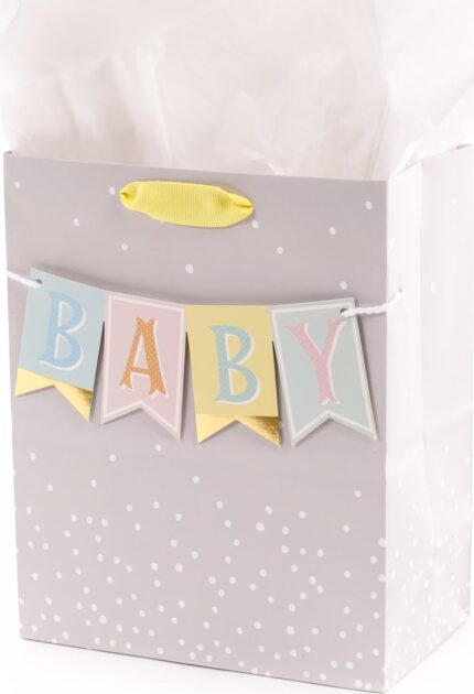 Hallmark medium baby gift bag with a "BABY" banner, foil accents, and a yellow ribbon handle, displayed with white tissue pap