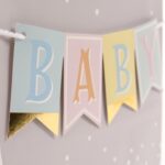 Hallmark medium baby gift bag with a "BABY" banner, foil accents, and a yellow ribbon handle, displayed with white tissue pap