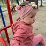 Three soft nylon baby headbands with flower embellishments in yellow, pink, and brown colors, suitable for infants.