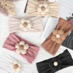 Three soft nylon baby headbands with flower embellishments in yellow, pink, and brown colors, suitable for infants.