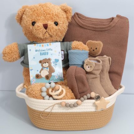 A 9-piece baby boy gift set including a teddy bear outfit, plush bear, pacifier clip, blue bib, and cotton basket.